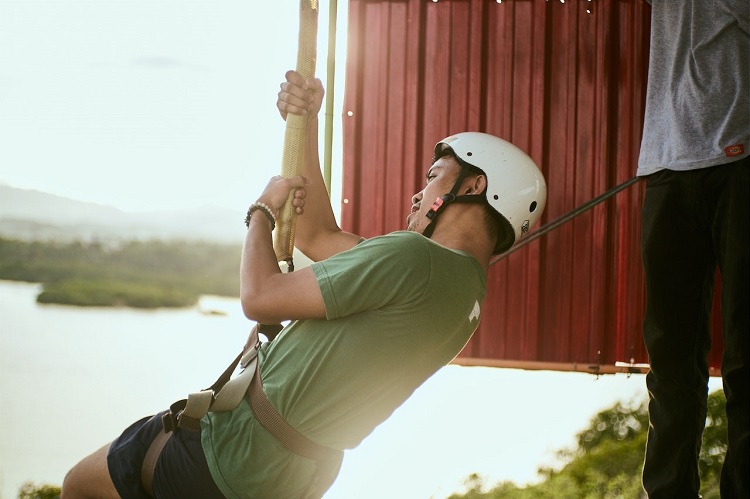 A man going on a zip line with a helmet on